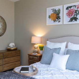 A cozy and well-decorated bedroom with a neatly made bed, pillows, and stylish artwork on the walls.