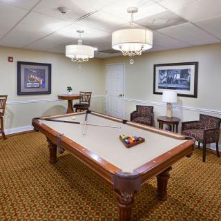 A cozy billiard room featuring a pool table, comfortable seating, and elegant lighting.