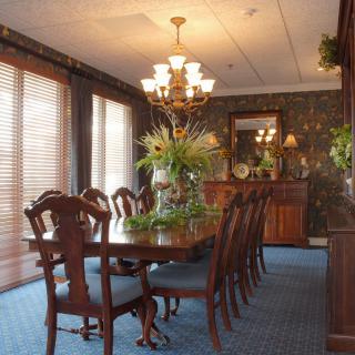 A traditional dining room with a large wooden table, surrounded by chairs and illuminated by an elegant chandelier.