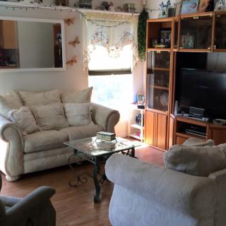 A cozy living room with comfortable sofas, a wooden entertainment center, and a television.