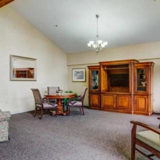 Spacious living room with a dining table, entertainment center, and chandelier.