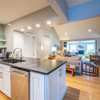 A modern open-space kitchen and living area with sleek countertops and warm wood flooring.