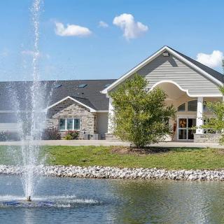 A building with a fountain in front and a pond, set against a blue sky.