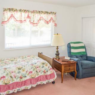 A cozy bedroom with a floral bedspread, armchair, and side table.