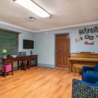 A cozy living room featuring a piano and a workspace, perfect for relaxation and creativity.