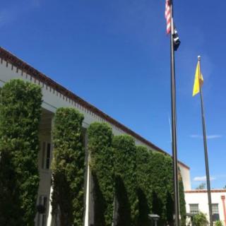 A building with ivy-covered walls and flags on a clear day.