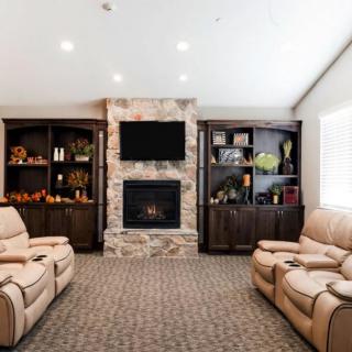 A cozy living room with recliner chairs, a stone fireplace, built-in bookshelves, and a television.