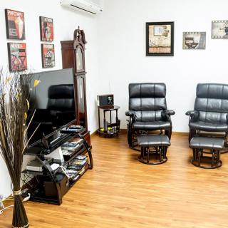 A modern living room with black leather chairs and a large television.