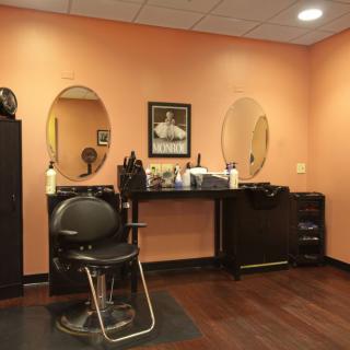 A cozy hair salon interior featuring a styling chair, mirrors, and salon equipment against orange walls.