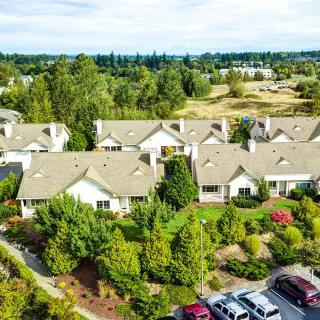 Aerial view of a suburban residential area with houses surrounded by greenery and a parking lot.