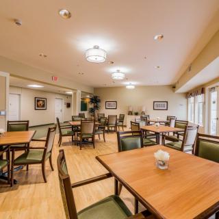 An empty dining room with neatly arranged tables and chairs, well-lit by overhead lighting.