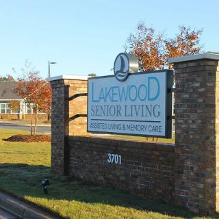 A sign for Lakewood Senior Living mounted on a brick wall in front of a building.
