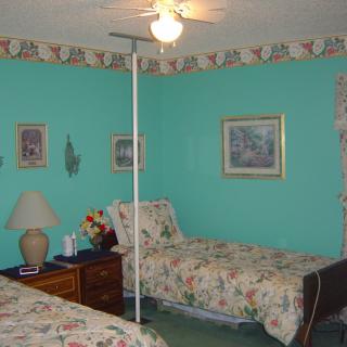 A cozy bedroom with turquoise walls and twin beds featuring floral bedding.