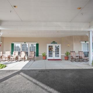 A covered entrance area with chairs and potted plants outside a building.