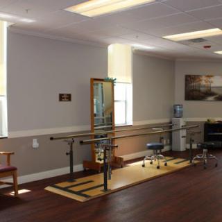 A well-equipped physical therapy room featuring parallel bars and seating.