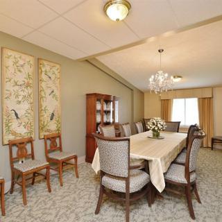 A traditional dining room with a large table and chairs, decorated with a chandelier and wall art.