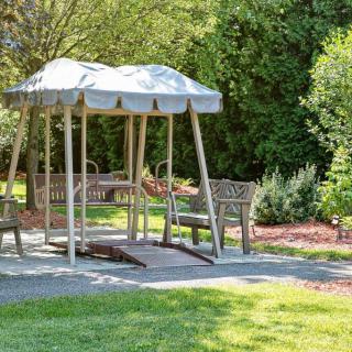 A tranquil garden setting with benches under a shaded canopy swing.