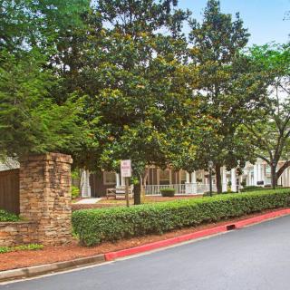 A peaceful street view with lush greenery and a building in the background.