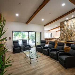 A modern living room featuring leather seating, a glass coffee table, and decorative wooden beams.