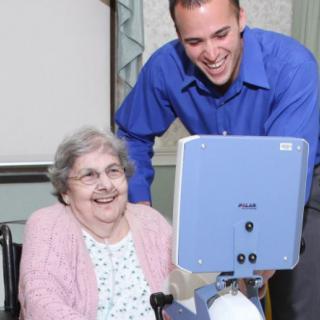 A young man shares a moment of joy with an elderly woman, engaging with technology.