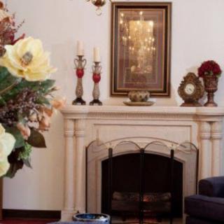 A cozy living room with a decorated fireplace, featuring flowers and candles.