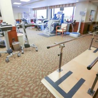 A well-equipped physical therapy and rehabilitation room with exercise machines and parallel bars.