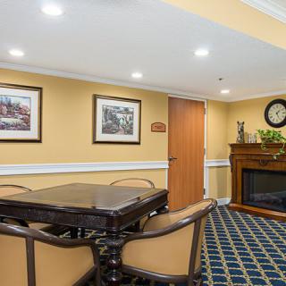 A cozy dining room with elegant decor, featuring a central table, chairs, artwork on the walls, and a fireplace.