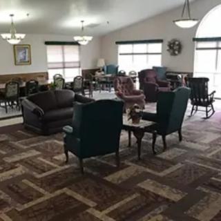 A spacious living room area with various chairs, sofas, and tables on a patterned carpet.