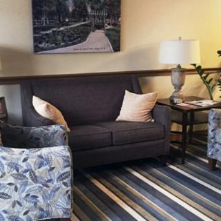 A cozy living room with a sofa, armchairs, and a striped carpet.