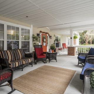 A spacious porch featuring comfortable seating with cushions and a variety of decorations.