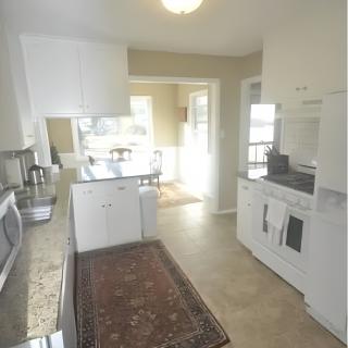A bright and modern kitchen with white cabinets, granite countertops, and various appliances.