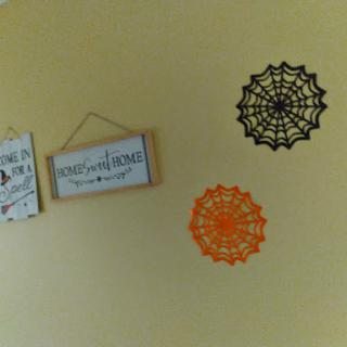 A cozy wall decorated with Halloween-themed spider webs and a cheerful sign.