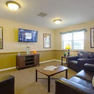 A cozy living room with leather sofas, a coffee table, and a television mounted on the wall.
