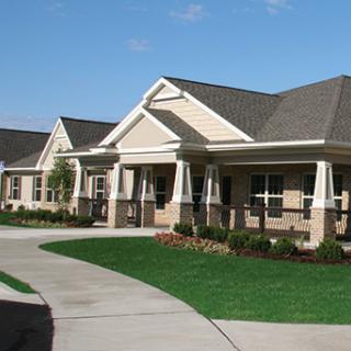 A view of a modern residential building with a well-maintained lawn and clear blue skies.