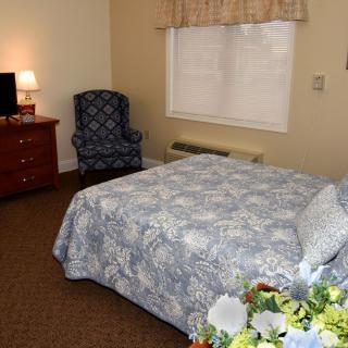 A cozy hotel room with a bed, armchair, and television.