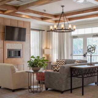 A cozy living room with stylish furniture, a chandelier, and ample natural light.