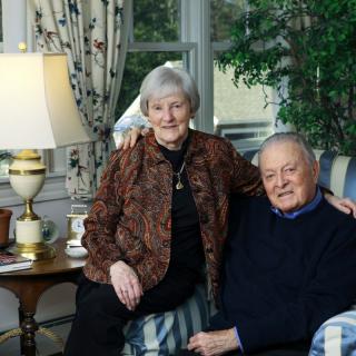 An elderly couple sitting together in a cozy living room.