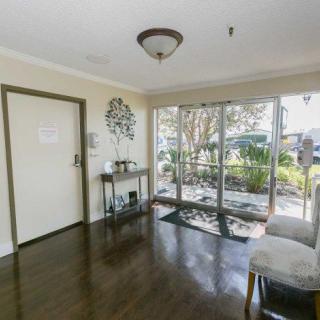 A bright entrance foyer with glass doors leading outside, featuring a table and a chair.