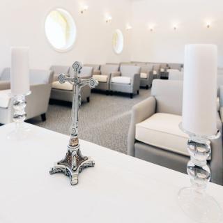A modern chapel interior featuring seating areas, a decorative cross, and candles.