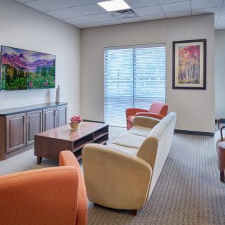 A modern waiting room with comfortable seating and decorative artwork.