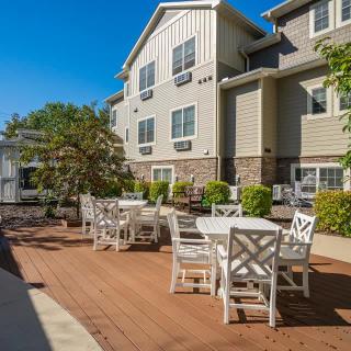 A sunny patio with outdoor seating in front of a residential building.