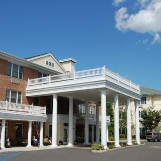 A building entrance with tall white columns under a clear blue sky.