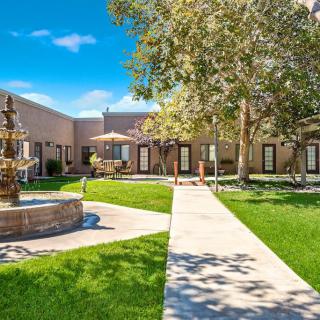 A serene courtyard with a fountain surrounded by well-maintained lawns and trees.