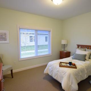 A cozy bedroom featuring a single bed, light green walls, and natural lighting.