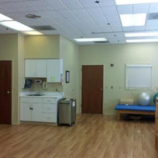 A clean rehabilitation room with exercise equipment and a sink area.