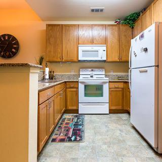 A cozy kitchen with wooden cabinets, featuring a refrigerator, oven, and microwave.