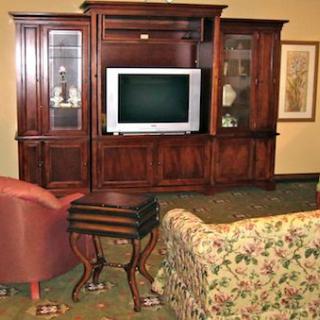 A cozy living room setup featuring a wooden entertainment center with a television, surrounded by comfortable seating.