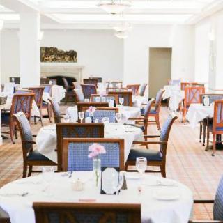 A spacious restaurant dining area with neatly arranged tables and chairs, adorned with white tablecloths.