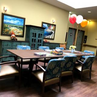A cozy dining area featuring a large table, colorful chairs, and vibrant balloons for a festive atmosphere.