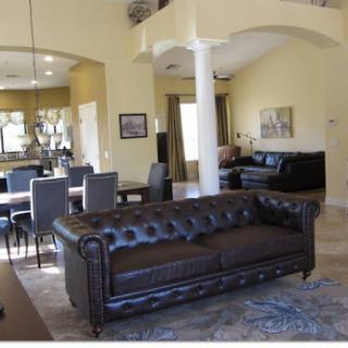 A stylish, modern living room featuring a luxurious brown leather sofa and a sleek dining area.
